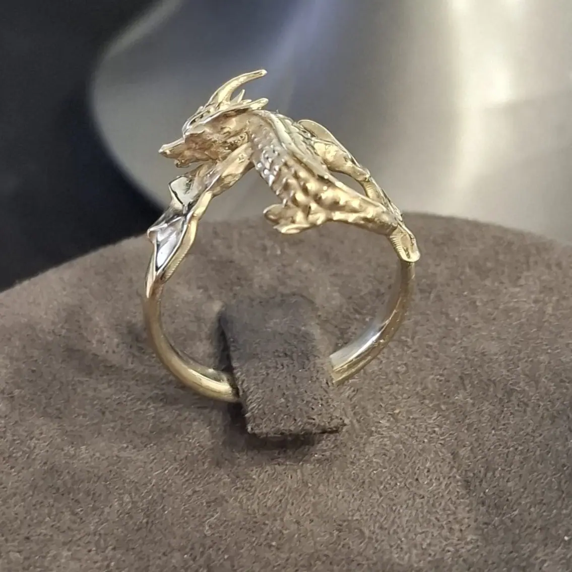 Gold dragon ring on a display stand, side view