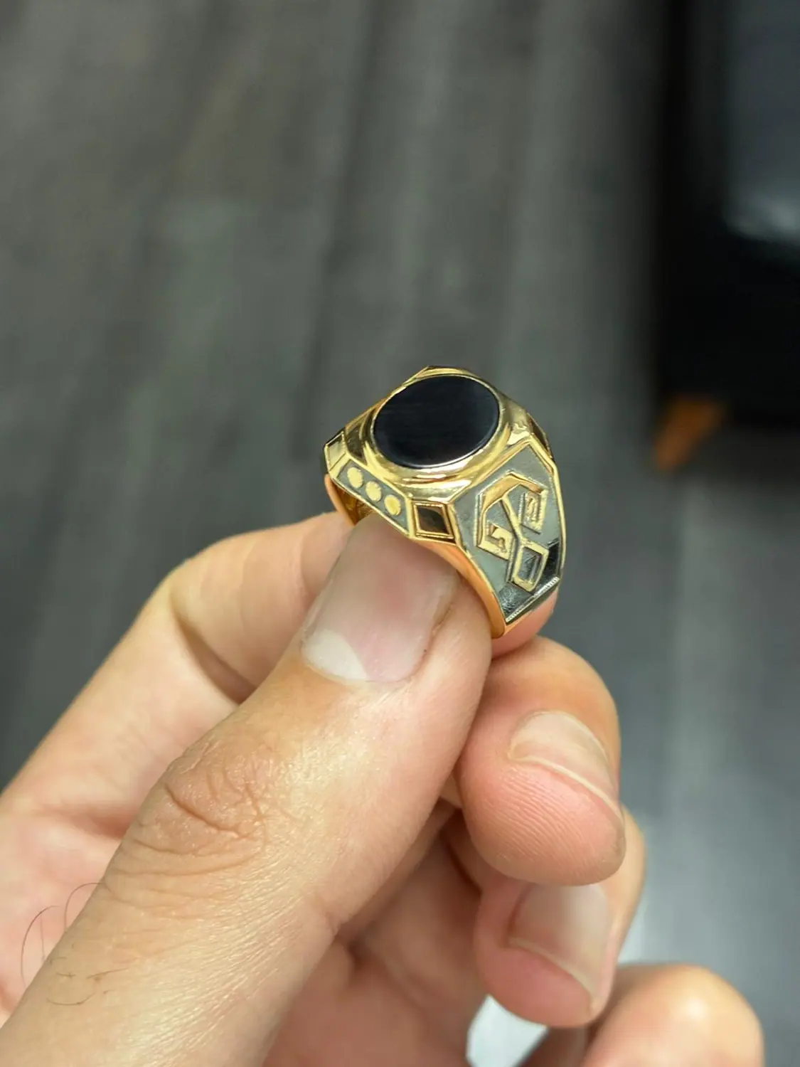 Finished gold signet ring with a black stone held in a hand