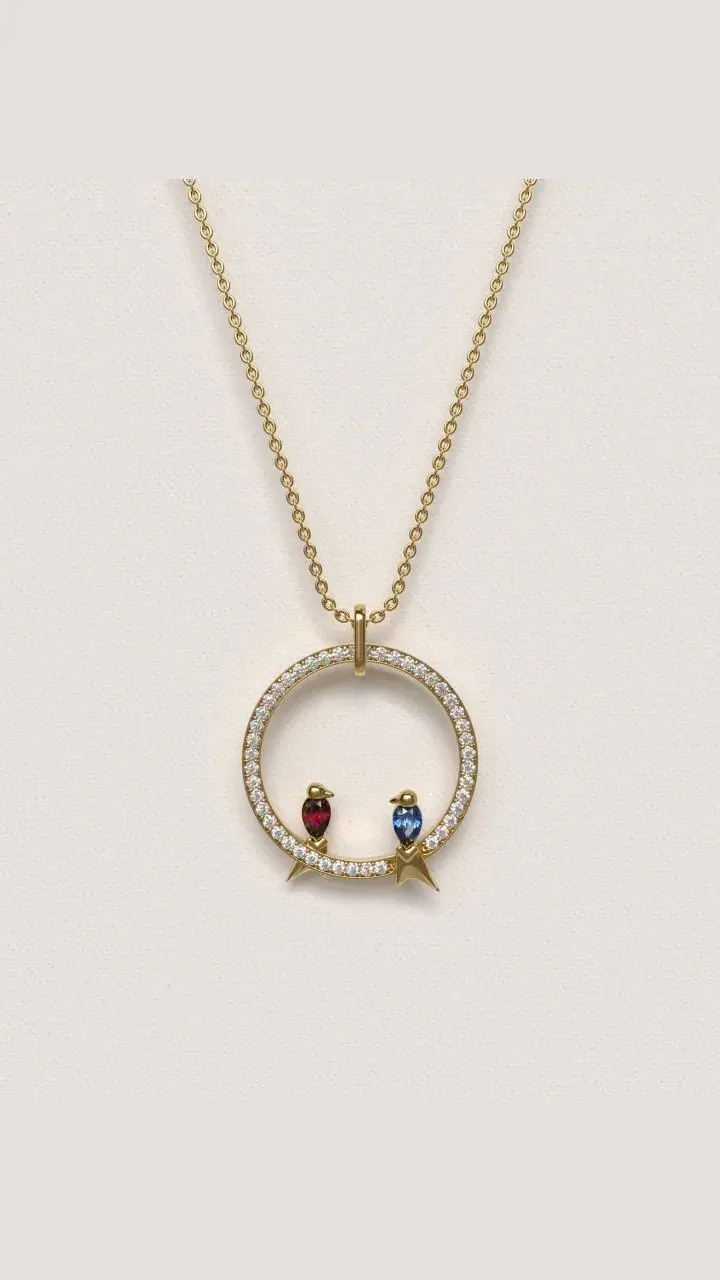 Gold circle pendant set with small stones and two tiny birds, one red and one blue