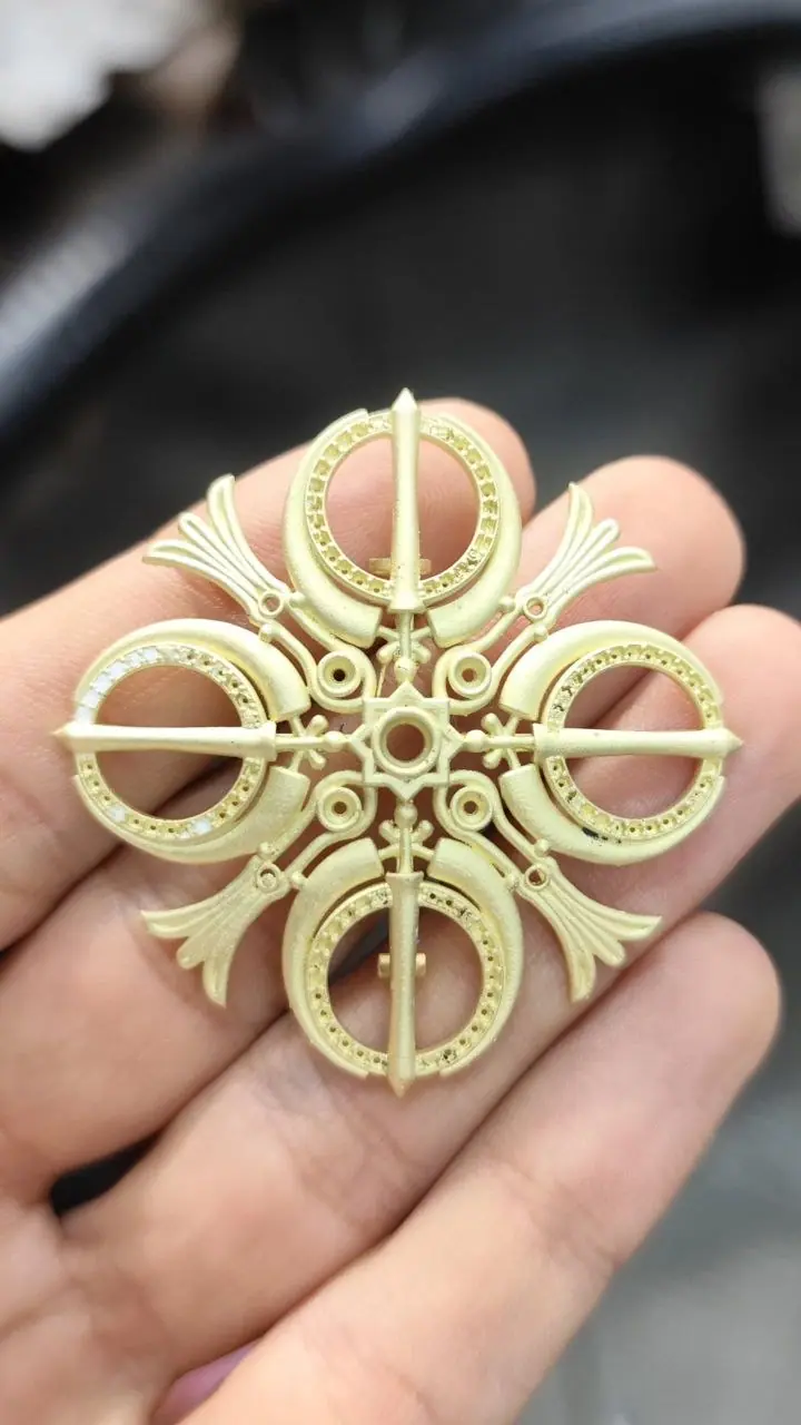 Adi Shakti brooch cast in raw gold, held in the hand